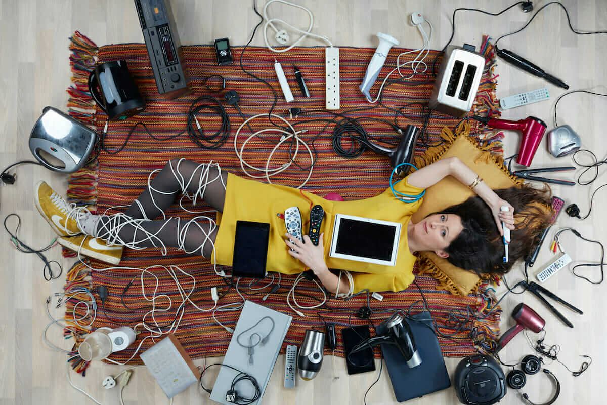 photo of Natalie Fee lying on a carpet covered with household electrical items by Gregg Segal for Recycle Your Electricals