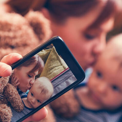 mother and child with soft toy adult and child photo on mobile phone