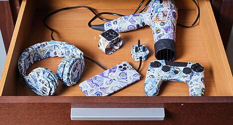 open wooden drawer of electrical items all wrapped in bank notes