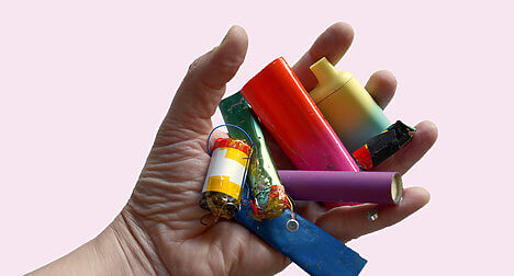 a light skinned hand open holding many disposable vapes