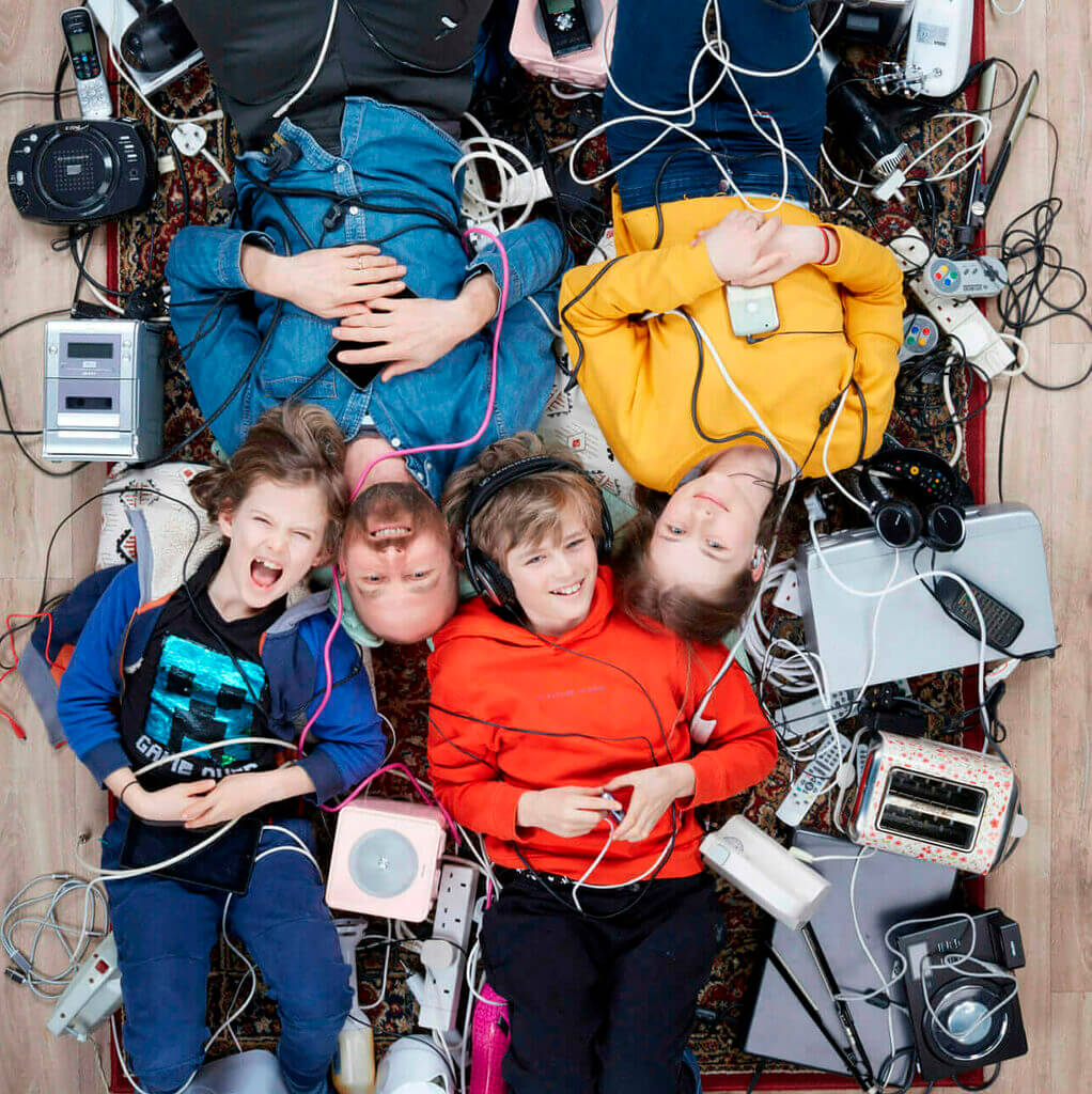 Material_Change_Rupert-Children4844-500x light skinned father and three children surrounded by electricals