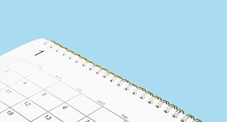 a close up of a paper calendar against a bright blue background