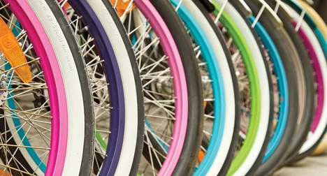 close up of many brightly coloured bicycle wheels in a row