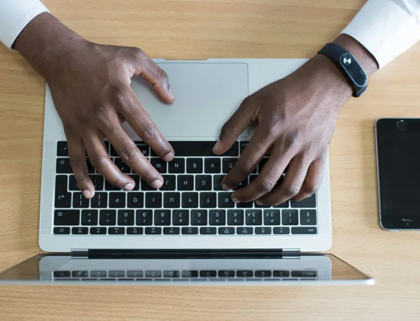 overhead shot of a laptop cytonn-photography-ZJEKICY5EXY-back up data overhead shot of a dark skinned man using a modern laptop