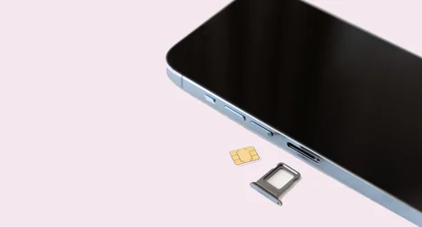 a close up of a mobile phone showing the slot where the SIM card goes as open and the SIM card lying next to it