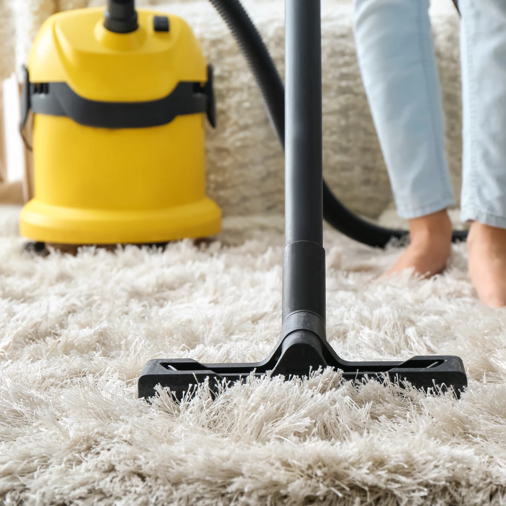yellow vacuum cleaner shutterstock_1364933420 1000px cropped front view of someone bare foot vacuuming a shag-pile rug with a black and yellow two part vacuum