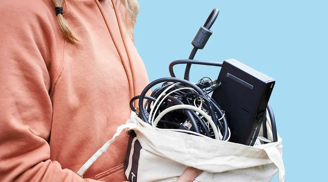 woman in a pink hoodie top holding a cloth bag full of cables